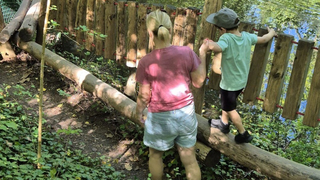 Mutter und Kind balancieren über einen Baumstamm